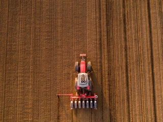 Foto op Plexiglas Aerial shot of a farmer seeding, sowing crops at field. Sowing is the process of planting seeds in the ground as part of the early spring time agricultural activities. © oticki