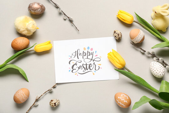 Greeting card with text HAPPY EASTER, painted eggs and tulips on grey background. Top view