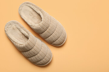 Pair of beige soft slippers on beige background. Top view