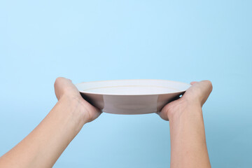 Blank plate in female hand isolated on blue background