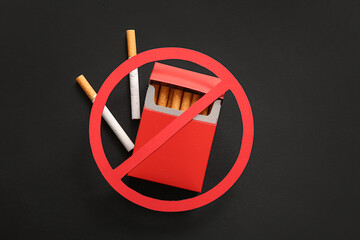Stop sign and pack of cigarettes on black background, closeup. Stop smoking concept. - obrazy, fototapety, plakaty