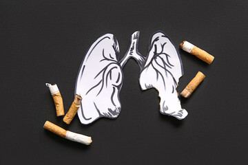 Paper lungs and cigarette butts on black background. Stop smoking concept.