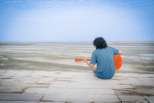 the people who playing guitar on the beach with dramatic tone