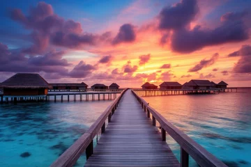 Selbstklebende Fototapeten Wooden jetty at sunset in tropical  island with water bungalows An amazing sunset landscape Picturesque summer sunset , Ai generated © Tanu