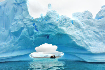 Tourists in Antarctica on a pontoon admiring an iceberg - obrazy, fototapety, plakaty