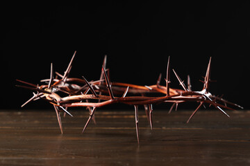 Crown of thorns on wooden table against black background, closeup. Good Friday concept