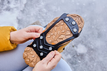 Rubber pads, anti-icing spikes for boots, are worn on trekking winter shoes to protect against slipping during icy conditions. - obrazy, fototapety, plakaty