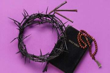 Crown of thorns with Bible, beads and nails on purple background. Good Friday concept