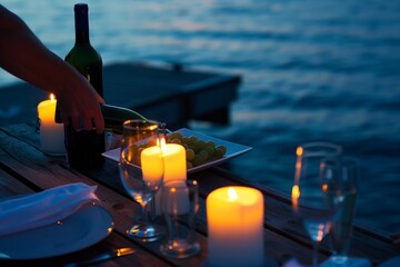 person serving wine at a candlelit dinner on a pier - obrazy, fototapety, plakaty