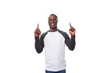 Naklejka premium young joyful african guy dressed in a black and white sweatshirt and jeans on a white background with copy space