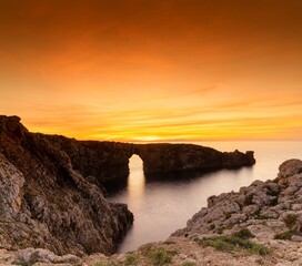view of the landmark stone arch of Pont d'en Gil on Menorca Island just after sunset