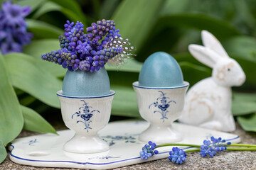 Oster-Arrangement mit blau gefärbten Eiern, Traubenhyazinthen-Strauß und Osterhasen