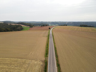 Aerial view of a long road between farm fiels in the countryside 