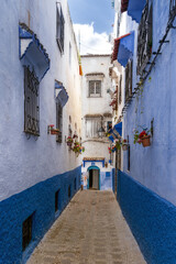 narrow alley leads through the historic city center of the blue city of Chefchaouen in northern...