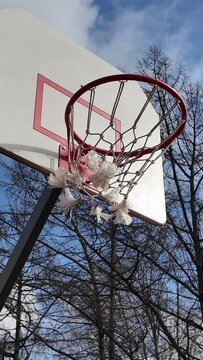 Throwing a ball into a basketball basket on an outdoor court