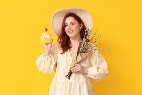 Beautiful young woman with pussy willow branches and toy chick on yellow background. Easter celebration
