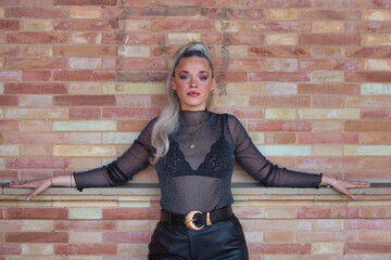 Pretty young blonde woman with a ponytail in her hair leaning with her arms outstretched on the...