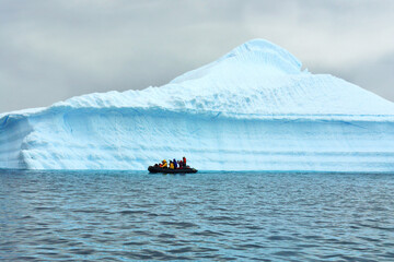 Tourists in Antarctica on a pontoon admiring an iceberg