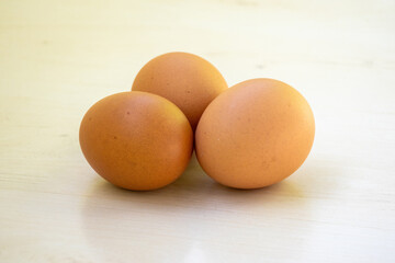 Three chicken eggs isolated on wooden surface
