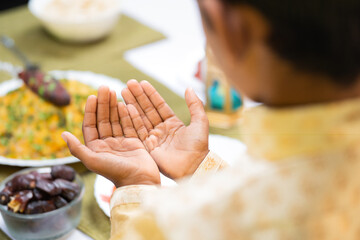 Shoulder shot of muslim kid praying to god during Ramadan festival celebration at home.