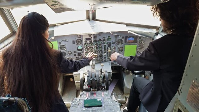 A woman and a man are in the cockpit of an airplane