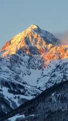 Alpenglow on a snowy mountain peak during sunrise