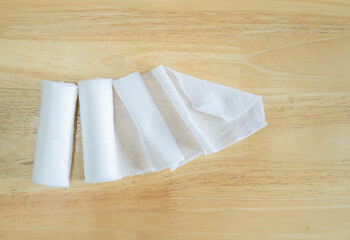 Close-up of white medical cotton gauze bandage on wooden background.