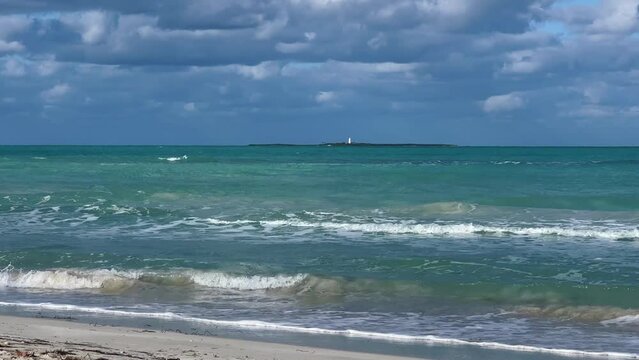 A beautiful Cuban beach in Varadero, Cuba, where you can see the waves and ocean waters on a cloudy day with the sun breaking through the clouds. Turquoise waves. 4K Video