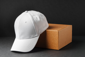 White Baseball Cap Beside Cardboard Box