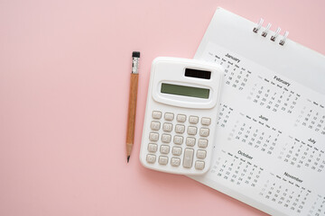 calculator, pencil on calendar with pink background including copy space, for accounting planning...