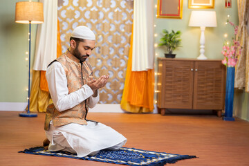 vertical shot of young indian muslim man doing holy namaz or Salah at home during ramdan festival - concept tredition, culture and festive celebration.