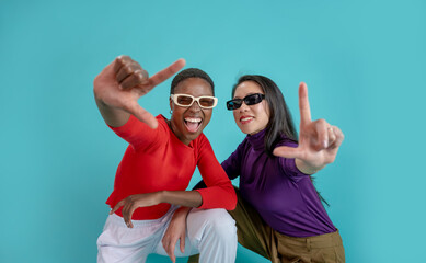 Young afro american and chinese woman wearing sunglasses over isolated background smiling making frame with hands and fingers with happy face. Creativity and photography concept. High quality photo