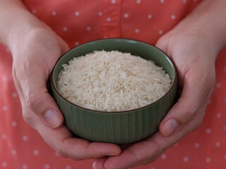 Woman holding green bowl full of rice in her hands.