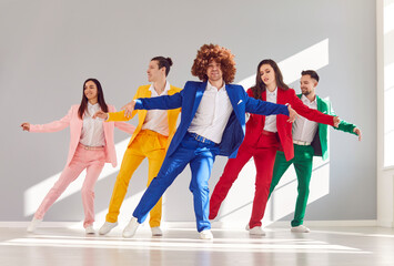 In step with style. Group of five cheerful people coordinated in dance line dance dressed in bright stylish suits. Beautiful creative people dancing showing teamwork, fashion, joy and rhythm of life. - obrazy, fototapety, plakaty