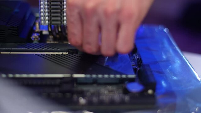 Computer technician removing protective film from motherboard heatsink. Process hardware upgrade of motherboard component. Stages of upgrading or assembling desktop computer. Shooting in slow motion.