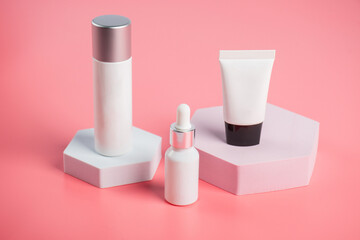 Plastic white tube for cream or lotion. Skin care or sunscreen cosmetic with stylish props on pink background.