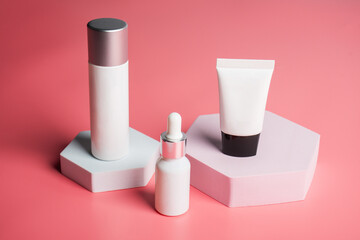 Plastic white tube for cream or lotion. Skin care or sunscreen cosmetic with stylish props on pink background.