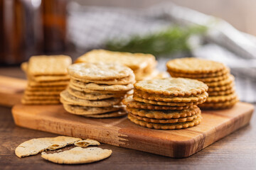 A stack of crackers neatly arranged on cutting board on wooden tabletop.
