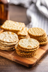 A stack of crackers neatly arranged on cutting board on wooden tabletop.