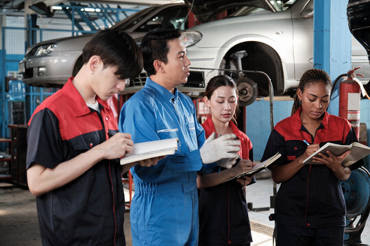 Specialist lecture. Male supervisor engineer describe automotive suspension fixing with mechanic worker staff teams for repair work at car service garage and maintenance jobs in automobile industry.