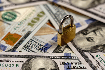 Padlock on hundred dollar bills. Financial security or lock concept.