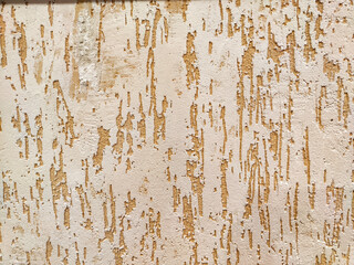 Peeling Beige Paint on a Rough Wall Texture. Weathered wall with flaking paint exhibiting aging