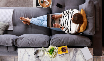 Relaxed young woman on sofa with laptop