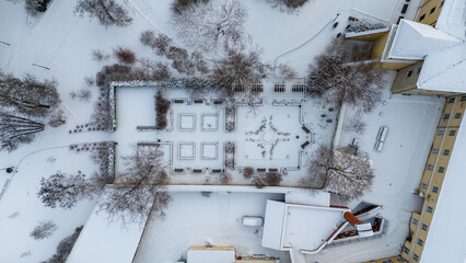 Drone photography of small public park with hedge covered by snow in a city during winter day