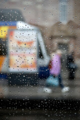 closeup of the rain drops of the window at the tramway station in the street. - 772906338