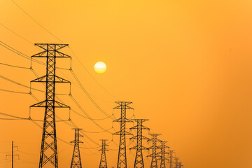 Electricity pillars against a colorful yellow sunset. Silhouette high voltage electric towers,...