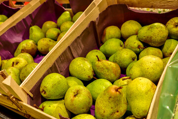 Pears at the Market. Fresh sweet organic pears in wooden box or basket on old white wooden retro table background. Autumn harvest of fruits. Top view. Food background. Organic farmer harvesting pears.