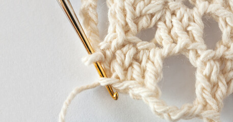 Close-up view of process of hand crocheting lace doily on metal gilded crochet hook from cotton...