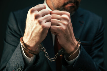 Handcuffed arrested businessman, closeup of male in business suit with handcuffs