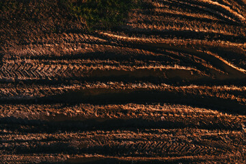 Tread marks, top view of tractor tire pattern in muddy ground of countryside dirt road from drone pov